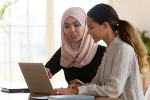muslim worker working with coworker on a computer